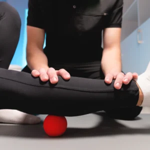 Therapist massaging leg with red ball.