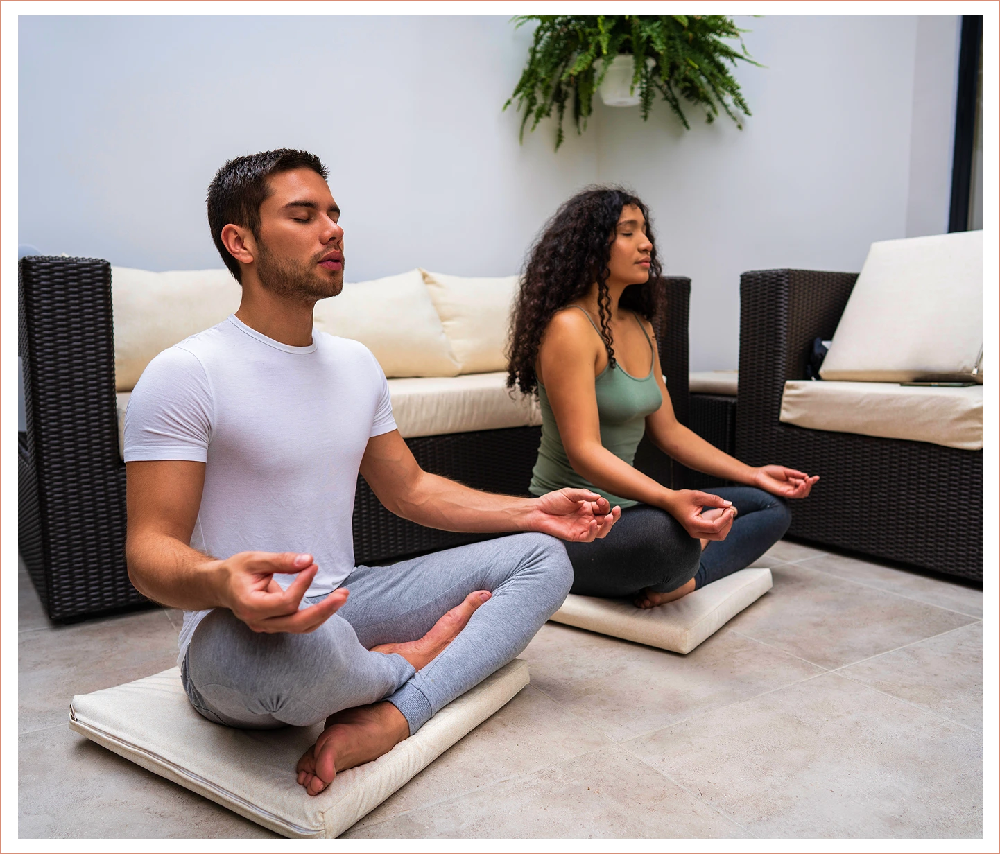 Two people meditating indoors on cushions.